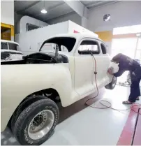  ??  ?? FINISHING TOUCHES ... A mechanic applies finishing touches to a restored car. The facility is open to other classic car owners, too.