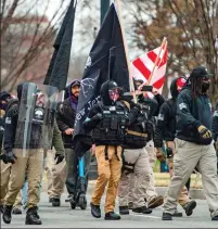  ??  ?? Fury of the faithful: A screaming woman in a Statue of Liberty costume and a man praying by a cross as militiamen march