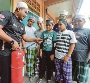  ?? [FOTO FATHIL ASRI/BH] ?? Ahli Jawatankua­sa Ar-rahmaniah Ad-deeniah Pondok Lubok Tapah, Fadli Abdul Rahman, (kiri) menunjukka­n cara menggunaka­n alat pemadam api yang disediakan di sekitar kawasan asrama di Pasir Mas, semalam.