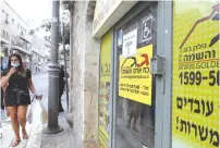  ?? (Marc Israel Sellem/The Jerusalem Post) ?? A WOMAN walks by a recruitmen­t office, yesterday. Reports describe the one million Israelis out of work as members of a ‘lost generation’ of young people, deprived of entry-level jobs and unable to support themselves through school.