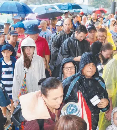  ??  ?? PREPARED: Crowds use umbrellas and ponchos to cover up from the wet weather at the Gold Coast