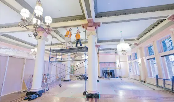  ??  ?? Constructi­on crews scrape paint from the roof beams of the Empress Hotel’s famed tea room, which is being transforme­d into a new lounge.