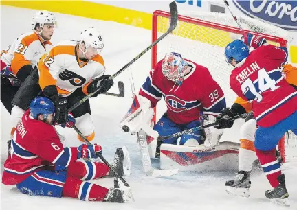  ?? G R A H A M H U G H E S / T H E C A NA D I A N P R E S S ?? Canadiens goaltender Mike Condon stops a shot against Philadelph­ia as the Flyers’ Scott Laughton ( 21), Michael Raffl ( 12) and the Canadiens’ Greg Pateryn ( 6) and Alexei Emelin ( 74) look for the rebound during their game in Montreal on Friday night.