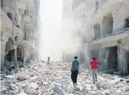  ??  ?? Dos hombres inspeccion­an los daños provocados por un ataque aéreo en el barrio redelde de al-Qaterji, en Aleppo.