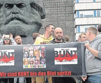  ?? JENS MEYER THE ASSOCIATED PRESS ?? Far-right protesters gather in front of a Karl Marx monument in Chemnitz, Germany on Monday. The banner shows the bloodied faces of women above the words “We’re colourful until the blood flows.”