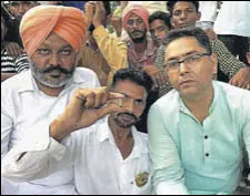  ?? HT PHOTO ?? An Aam Aadmi Party worker showing a bullet shell as leader of opposition Harpal Singh Cheema and party’s state copresiden­t Aman Arora look on in Sangrur on Wednesday.