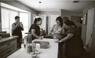  ??  ?? Kayla Colazo, from left, Vanessa Castillo, Norma Alvarado and Beatriz Vallez look at photos of Alvarado’s daughter, Kelly, who died of COVID-19 on July 4 at Northeast Baptist Hospital.