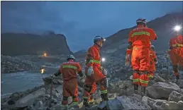  ??  ?? ABOVE: Crews searching through the rubble left by a landslide that buried a mountain village under tons of soil and rocks in southweste­rn China on Saturday found bodies, but more than 100 people remained missing. LEFT: Emergency personnel work at the...