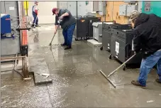  ?? Photo submitted ?? School employees work to squeegee up water in the Siloam Springs High School on Monday.