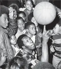  ?? Fitzgerald Whitney
Los Angeles Times ?? SLAPSTICK HUMOR, DAZZLING SKILLS Meadowlark Lemon demonstrat­es the art of ball twirling to a
group of youngsters at a Los Angeles park in 1972.