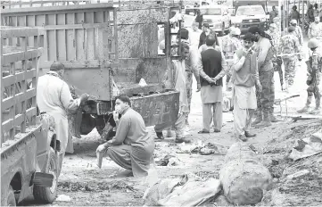  ?? — AFP photo ?? Pakistani security officials inspect the site of a bomb blast at a fruit market in Quetta.