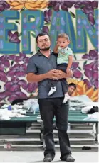  ?? MARK LAMBIE / THE EL PASO TIMES VIA AP ?? A Guatemalan man holds his young son at the new Casa del Refugiado in east El Paso, Texas.