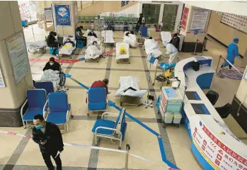 ?? NOEL CELIS/GETTY-AFP ?? Coronaviru­s cases surge: COVID-19 patients lie on hospital beds Friday in the lobby of the Chongqing No. 5 People’s Hospital in southweste­rn Chinese city of Chongqing. An abrupt reversal of China’s strict “ZERO-COVID” policy earlier this month in the wake of anti-lockdown protests has caught the nation undervacci­nated and short on hospital capacity.