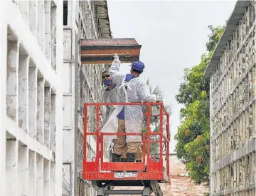  ??  ?? Brasil. Trabajador­es de Río de Janeiro colocan el ataud de una de las víctimas de covid-19 en un cementerio. La pandemia también está golpeando a este país suramerica­no.