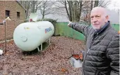  ??  ?? Rolf Bernhardt zeigt, wie nah der Tank mit der demolierte­n Leitung am Vereinshau­s steht.