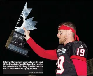  ?? — The Canadian Press ?? Calgary Stampeders' quarterbac­k Bo Levi Mitchell hoists the West Division Trophy after they defeated the Winnipeg Blue Bombers in the CFL West Final in Calgary, Sunday,