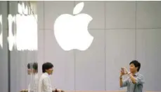  ?? — Reuters ?? A man uses his phone to take pictures outside an Apple store in Beijing.