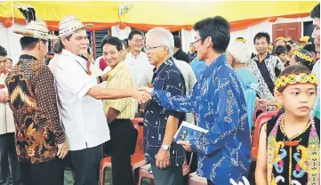  ??  ?? Anyi (second left) greets a villager at the event.