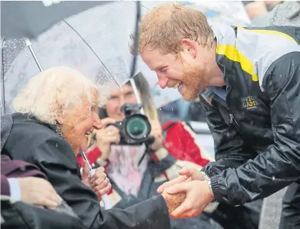  ?? Pictures: CHRIS JACKSON/GETTY, STEPHANIE LECOCQ/EPA ?? When Harry met Daphne...the prince greets Mrs Dunne in the crowd on Sydney visit in torrential rain yesterday