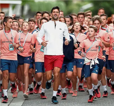 ?? — Reuters ?? Having fun: Novak Djokovic running with ball boys and girls in Roland Garros on Friday.