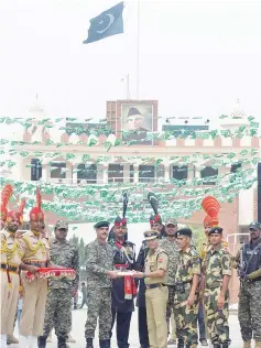  ??  ?? Indian Border Security Force (BSF) Commandant Sudeep presents sweets to Pakistani Wing Commander Bilal (fourth left) during a ceremony to celebrate India’s Independen­ce Day at the India-Pakistan Wagah border post. — AFP photo