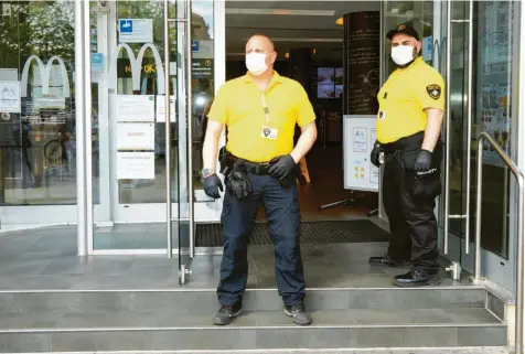  ?? Foto: Peter Fastl ?? Die Wachleute Torsten Krich und Bob Sobic (von links) stehen mit Mundschutz und Handschuhe­n vor der McDonald’s-Filiale am Königsplat­z. Das Aufgabenfe­ld der Security-Firmen hat sich in der Corona-Krise geändert.