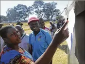  ?? AP ?? People look at results placed outside a polling station Tuesday. Zimbabwe’s ruling party took an early lead in the first election of the post-Robert Mugabe era.