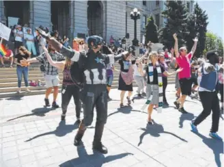  ?? John Leyba, The Denver Post ?? “Captain America” joins in a dance to celebrate World Refugee Day on the steps of the state Capitol on Tuesday morning.