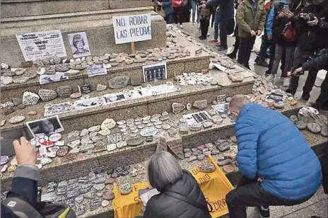  ??  ?? ACTO. Participan­tes de la movilizaci­ón colocan las piedras con los nombres de fallecidos por COVID-19 en la Plaza de Mayo, en Buenos Aires.