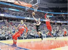  ?? ROB CARR/GETTY IMAGES ?? Heat guard Goran Dragic scores on a layup between Wizards defenders Otto Porter Jr. and John Wall during the first half of Friday night’s game.