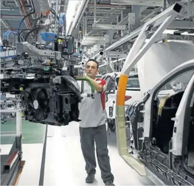  ?? REUTERS / GUSTAU NACARINO ?? Un operario de la fábrica de Seat de Martorell (Barcelona) instala un motor en el chasis de un ‘León’.