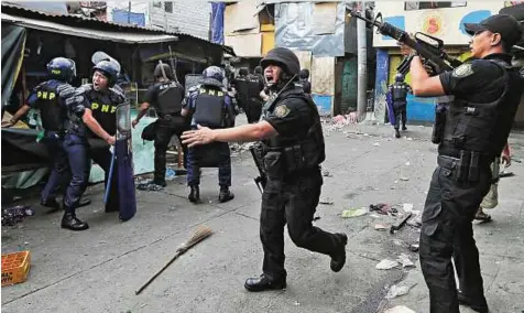  ?? AP ?? SWAT officers conduct a house-to-house search for residents who resisted the demolition of their shanties at an informal settlers’ community at suburban Caloocan city north of Manila, Philippine­s, yesterday. A policeman was injured and at least three...