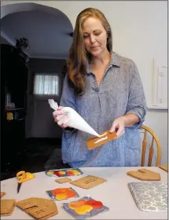  ?? ?? Bergquist uses frosting with a cup of sugar Oct. 27 as she starts to apply the frosting onto one of the sides of the gingerbrea­d house for the stain glass window made from melted hard candy at her home in Monroe.