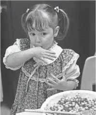  ?? THE COMMERCIAL APPEAL ?? Dotsy Liles’ class of 3-year-olds made Mother’s Day lunch for their moms on May 10, 1984, at Highland Street Preschool. The menu included tuna fish, brownies, carrot sticks, fruit salad and deviled eggs. They also decorated their classroom with balloons and put down plates and placemats they decorated. Elizabeth Holloway “tastes” the fruit salad.