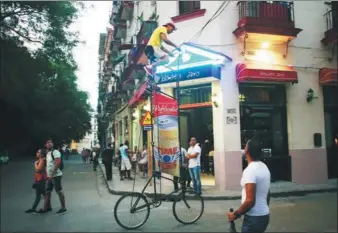  ?? ALEXANDRE MENEGHINI / REUTERS ?? Felix Guirola rides his homemade bike with an advertisin­g banner for a Dutch energy drink in Havana, Cuba. Guirola hopes to one day win the Guinness World Record for the tallest ridable bike.