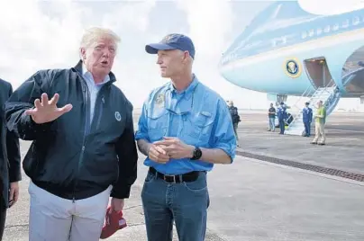 ?? EVAN VUCCI/AP ?? Gov. Rick Scott, right, looks on as President Donald Trump talks with reporters Monday after arriving at Eglin Air Force Base.