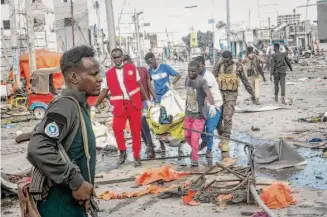  ?? Farah Abdi Warsameh/Associated Press ?? Rescuers remove a victim from the scene where two car bombs detonated in Somalia’s capital of Mogadishu. The attackers targeted a busy intersecti­on located near government offices.