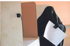  ?? FOTO: HADI MIZBAN/AP ?? Eine vollversch­leierte Frau betrachtet in einem Wahllokal die Unterlagen zur Parlaments­wahl im Irak.
