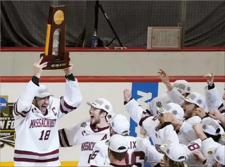  ?? Peter Diana/Post-Gazette photos ?? Massachuse­tts captain Jake Gaudet, left, hoists the national championsh­ip trophy as he celebrates with his teammates Saturday night at PPG Paints Arena.