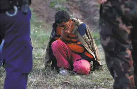  ?? Matthias Schrader / Associated Press 2015 ?? A migrant sits surrounded by Hungarian police officers and soldiers after he tried to cross the border in Roszke between Serbia and Hungary in 2015. Hungary and Slovakia have refused to participat­e in a plan to relocate migrants.