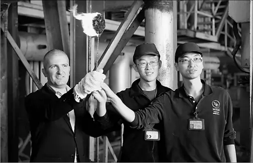  ?? PHOTOS PROVIDED TO CHINA DAILY ?? Cyril Ruiz-Moise (left) demonstrat­es a bottle from the assembly line with co-workers as if holding a relay torch.