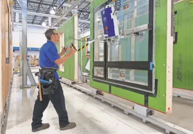  ?? PHOTOS BY NICK PANETTA/BLUEPRINT ROBOTICS ?? Scott Harting uses a vacuum lift assist, which allows him to precisely install heavy windows in a controlled environmen­t.