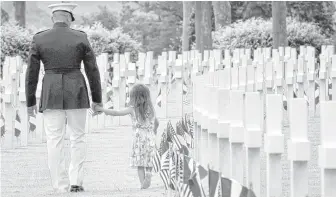  ?? Virginia Mayo / Associated Press ?? A U.S. Marine and a girl walk among headstones of World War I dead at a Memorial Day event at the Aisne-Marne American Cemetery in Belleau, France, where 474 U.S. Marines are buried.
