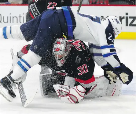  ?? — THE ASSOCIATED PRESS ?? Winnipeg Jets’ Quinton Howden collides with Carolina Hurricanes goalie Cam Ward as he tries to make a save during the first period of their game Sunday in Raleigh, N.C.