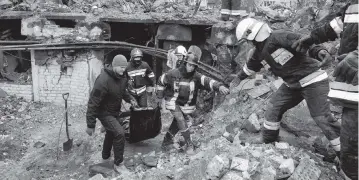  ?? EFREM LUKATSKY AP ?? Emergency workers remove the body of a resident of a multistory building destroyed in a Russian air raid at the beginning of the Russia-Ukraine war in Borodyanka, close to Kyiv, Ukraine, on Saturday.