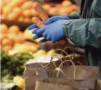  ?? FRANK AUGSTEIN AP ?? Handling food amid the coronaviru­s pandemic is critical to trying to keep healthy. Medical experts recommend wearing gloves in the supermarke­t and washing your hands and fruits and vegetables that you buy when you return home.
