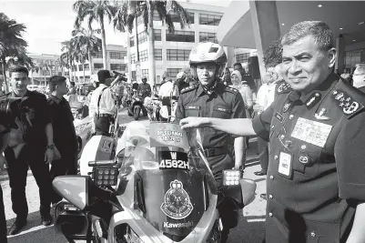  ??  ?? KHALID (kanan) melekatkan pelekat kempen Op Selamat 10/2017 pada motosikal polis pada majlis Pelancaran Op Selamat sempena Tahun Baru Cina 2017 di Persada Plus kelmarin. GambarBern­ama