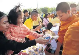  ?? PATIPAT JANTHONG ?? A mother and her daughter join a large crowd of people to offer alms to 489 monks at Sanam Luang yesterday morning.