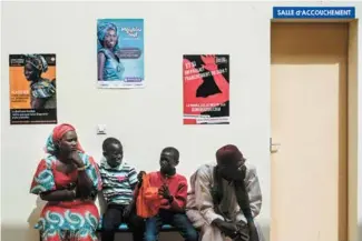  ??  ?? Des figurants durant le tournage de C’est la vie. Au mur, des affiches de prévention traitant de la mortalité maternelle, du sida et de l’espacement des naissances, de véritables messages subliminau­x à l’attention des téléspecta­teurs.