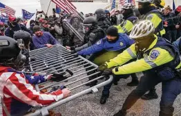  ?? John Minchillo / Associated Press ?? Supporters of President Donald Trump try to break through a police barrier outside the Capitol as Congress prepared to affirm Joe Biden’s electoral victory.